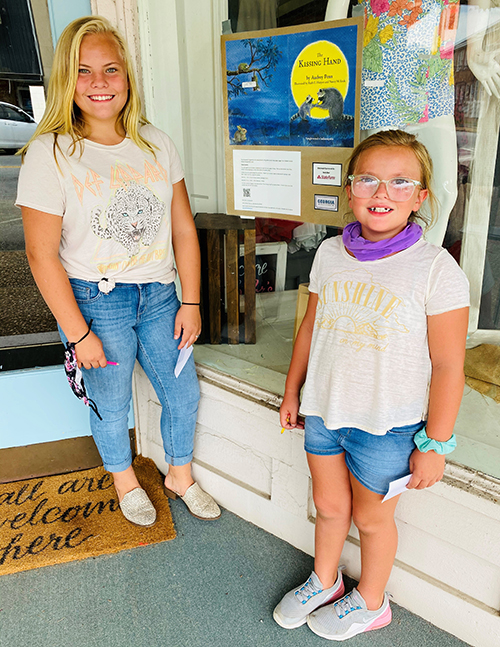 Hahira Main Street Director Jennifer Price's two daughters in front of a downtown storefront participating in the StoryWalk program.